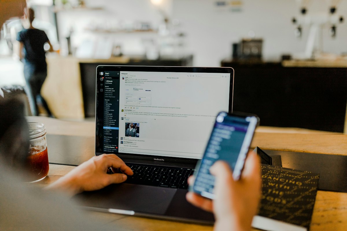 Person bruger telefon og computer derhjemme
